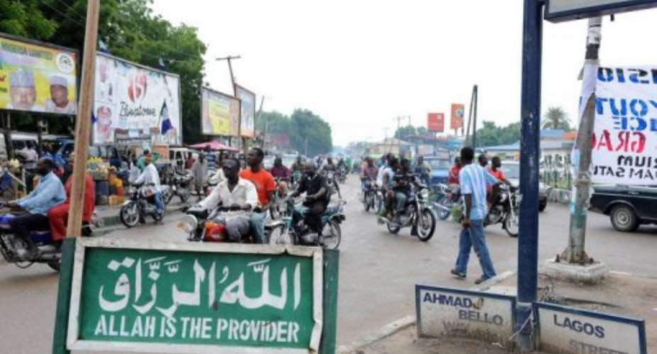 Public transport motorcylists drive past an Islamic inscription on a sign post in Maiduguri.  By Pius Utomi Ekpei (AFP/File)