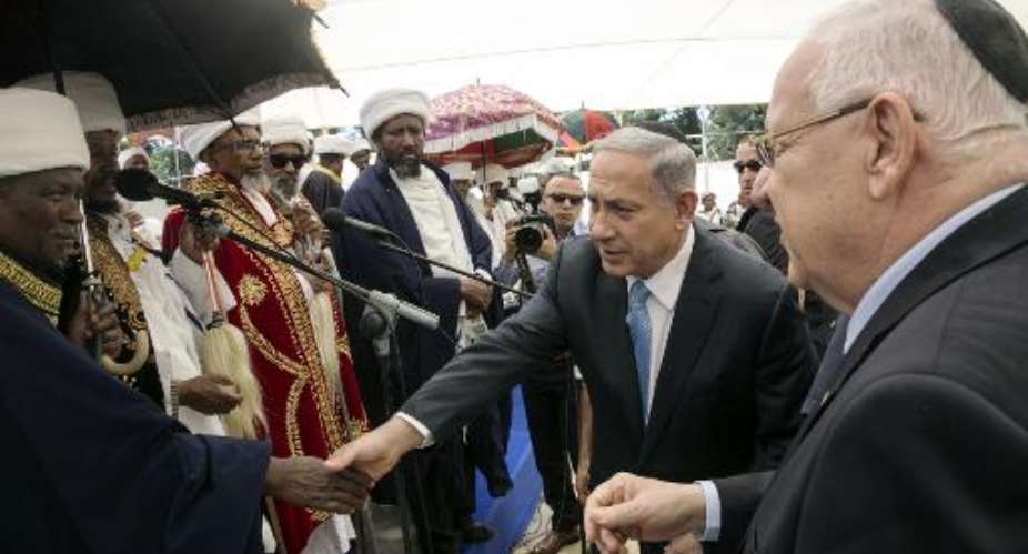 Israeli Prime Minister Benjamin Netanyahu (C) and President Reuven Rivlin (R) shake hands with Israelis of Ethiopian descent during a ceremony on Mount Herzl in Jerusalem on May 17, 2015.  By Baz Ratner (Pool/AFP)