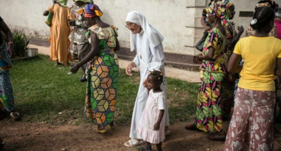 Italian nun Sister Maria Concetta Esu, 81, walks with a young girl after attending mass at the Catholic Church of Zongo, a small village in the Equatorial region of the Democratic Republic of Congo, on June 21, 2015.  By Federico Scoppa AFP