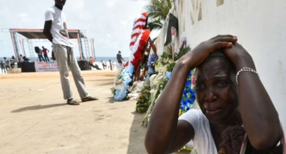A woman cries next to wreaths of flowers in front of the Etoile du Sud hotel on March 20, 2016 during a tribute to the victims of an attack that killed 19 people on March 13 on Ivory Coast's Grand Bassam resort.  By Sia-Kambou AFPFile
