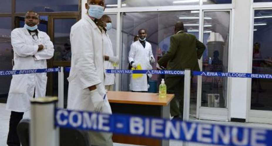 Medical staff wearing protective masks wait for passengers arriving from Guinea at Abidjan's airport on October 20, 2014.  By Issouf Sanogo AFPFile