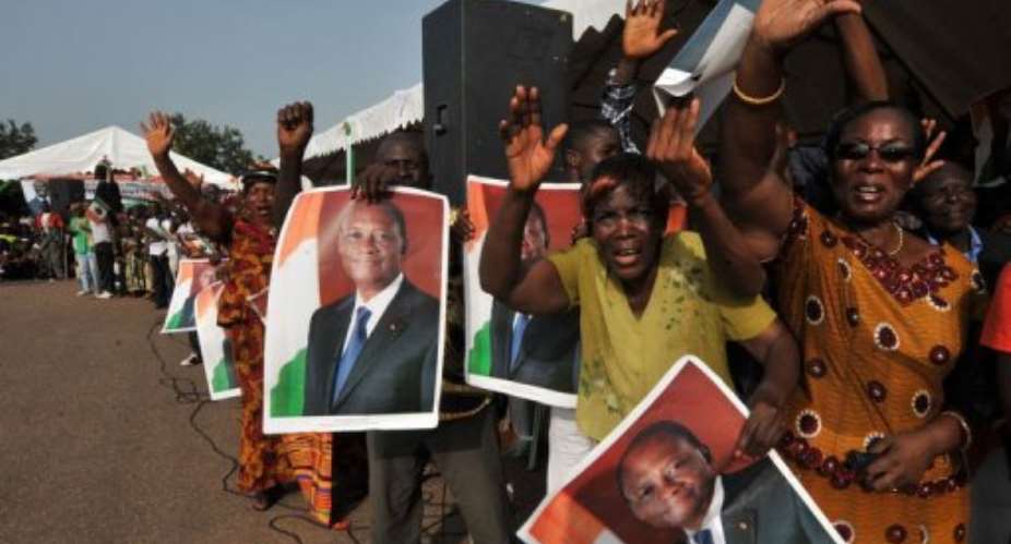 Supporters of Ivorian President Alassane Ouattara hold posters portraying him upon his arrival on April 22, in Guiglo.  By Sia Kambou AFPFile