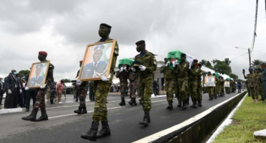 Ivory Coast soldiers carry coffins and pictures of their comrades killed in a brazen jihadist attack last month.  By SIA KAMBOU AFP