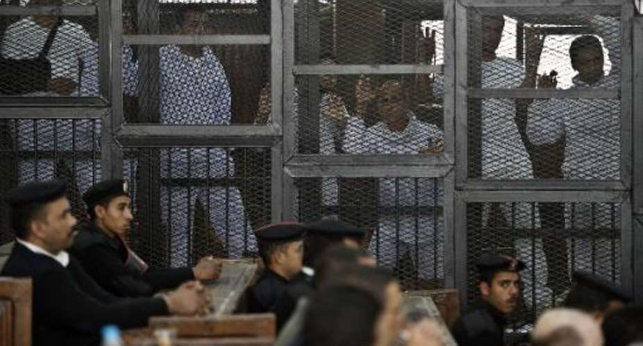 Australian journalist Peter Greste 3rd from R of Al-Jazeera and his colleagues stand inside the defendants cage during their trial for allegedly supporting the Muslim Brotherhood at Cairo's Tora prison on March 5, 2014.  By Khaled Desouki AFPFile