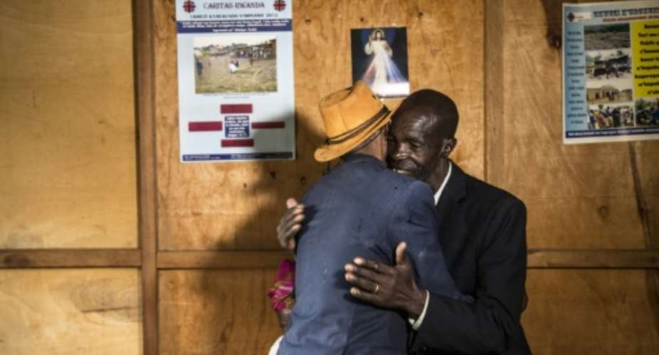 Jean-Bosco Gakwenzire, 65, of Tutsi ethnicity, embraces his old school mate Pascal Shyirahwamaboko R, 68 with his wife Rose hidden, both Hutu.  By JACQUES NKINZINGABO AFP