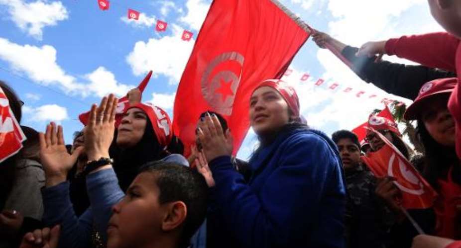 Tunisians wave their national flag and chant slogans during a march against extremism outside Tunis' Bardo Museum on March 29, 2015.  By Fethi Belaid AFP