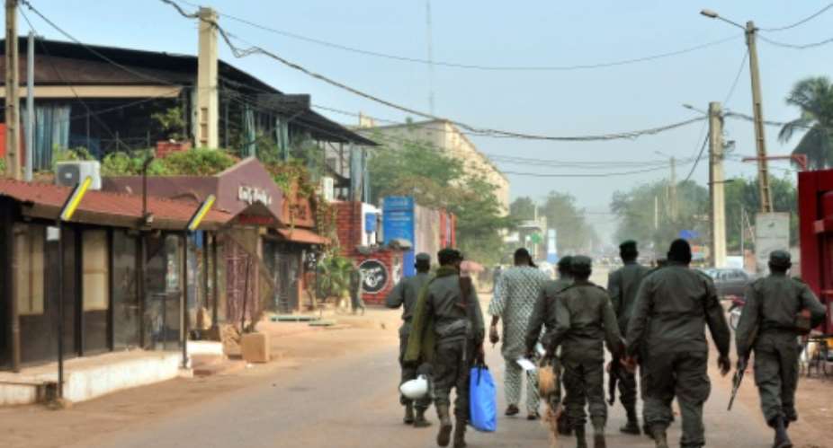 Members of Malian security walk past La Terrasse restaurant, on the left with the blue curtains, in the capital Bamako on March 7, 2015.  By Habibou Kouyate AFPFile