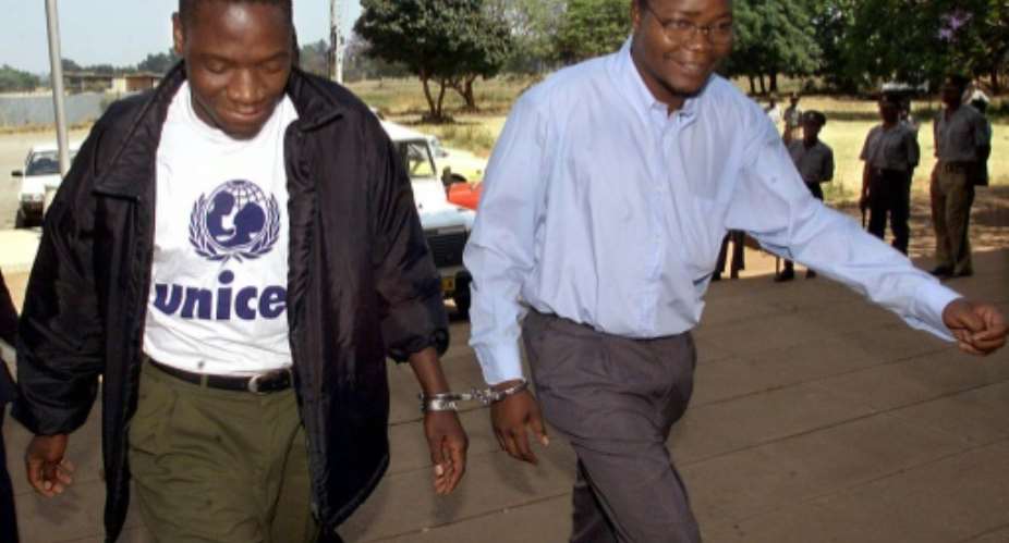 Job Sikhala, right, is handcuffed to fellow opposition MP Tafadzwa Musekiwa as they head into court in 2000 for allegedly threatening to use violence to overthrow the government. The case was dismissed.  By ODD ANDERSEN AFP