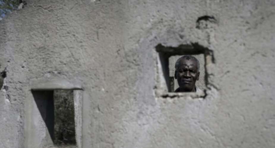 Jochonia Moyo, a survivor of the 'Gukurahundi' massacres, shows how people were packed into a holding cell at the now disused army barracks at Bhalagwe camp.  By ZINYANGE AUNTONY AFP