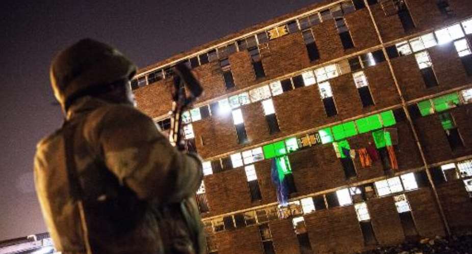 Soldiers back up police searching for drugs and weapons during a raid at Madoda Hostel in the Alexandra township of Johannesburg on April 23, 2015.  By Gianluigi Guercia AFP