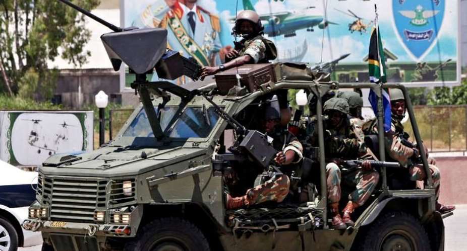 South African army soldiers patrol past a billboard with a picture of Moamer Kadhafi in Tripoli.  By Mahmud Turkia (AFP)