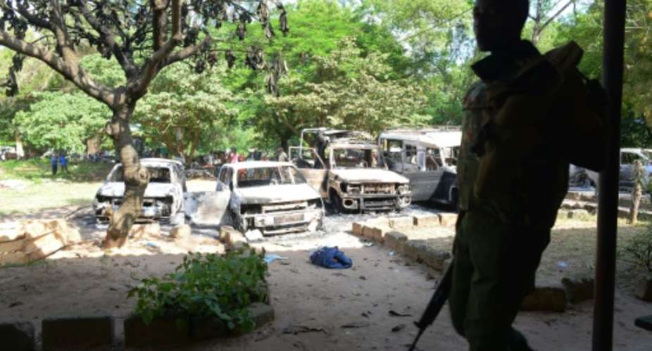 Kenya police observe the remains of burnt-out cars at a police station in Mpeketoni, Lamu county on June 16, 2014.  By Simon Maina AFPFile