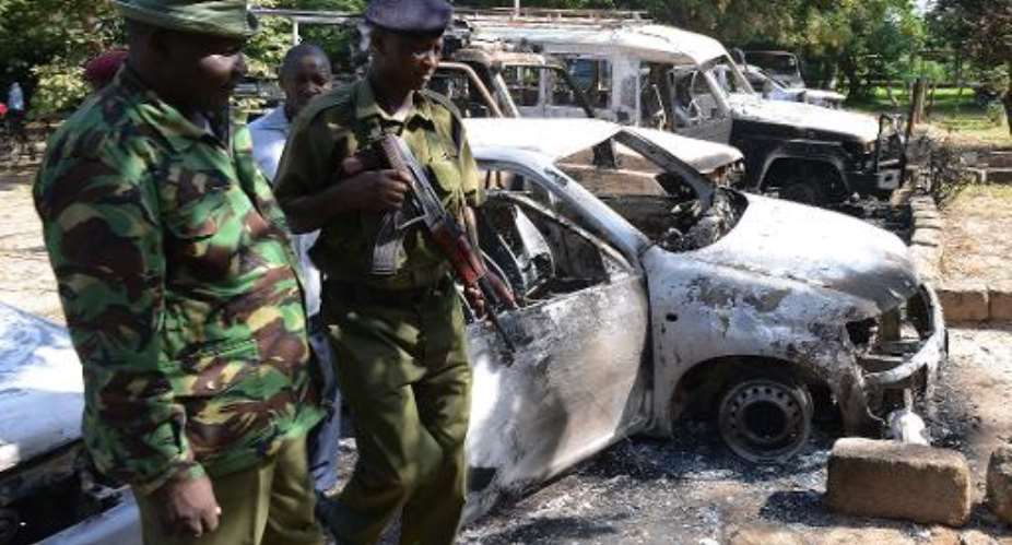 Kenyan police observe the remains of burnt-out cars at a police station in Mpeketoni, in the coastal county of Lamu on June 16, 2014.  By Simon Maina AFPFile