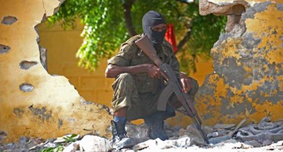 A Somali soldier stands guard next to the site where Al Shebab militants carried out a suicide attack against a military intelligence base in Mogadishu on June 21, 2015.  By Mohamed Abdiwahab AFP