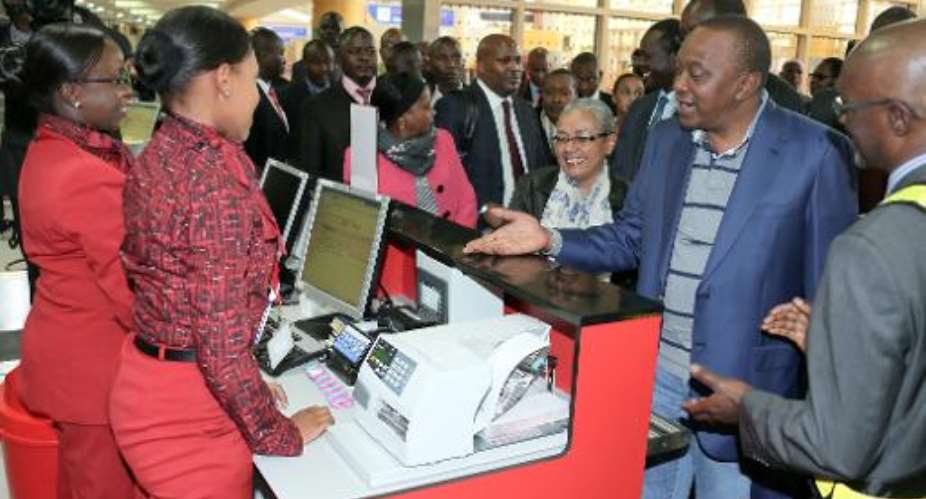 Kenyan President Uhuru Kenyatta 2nd-R and First Lady Margaret Kenyatta check in alongside other passengers at Nairobi airport as they head to the Hague on October 7, 2014.  By PSCU PSCUAFP