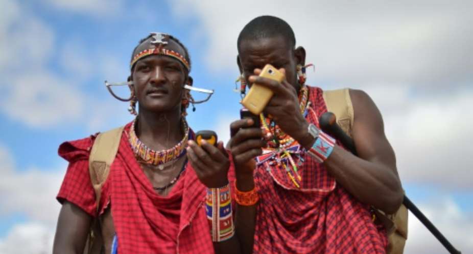 Kenyan Maasai 'Morans' warriors relay the GPS coordinates of the location of two-young lionesses they have been tracking on foot in the surrounding scrub, at the Selenkay Reserve, not far from Mount Kilimanjaro.  By Tony Karumba AFP