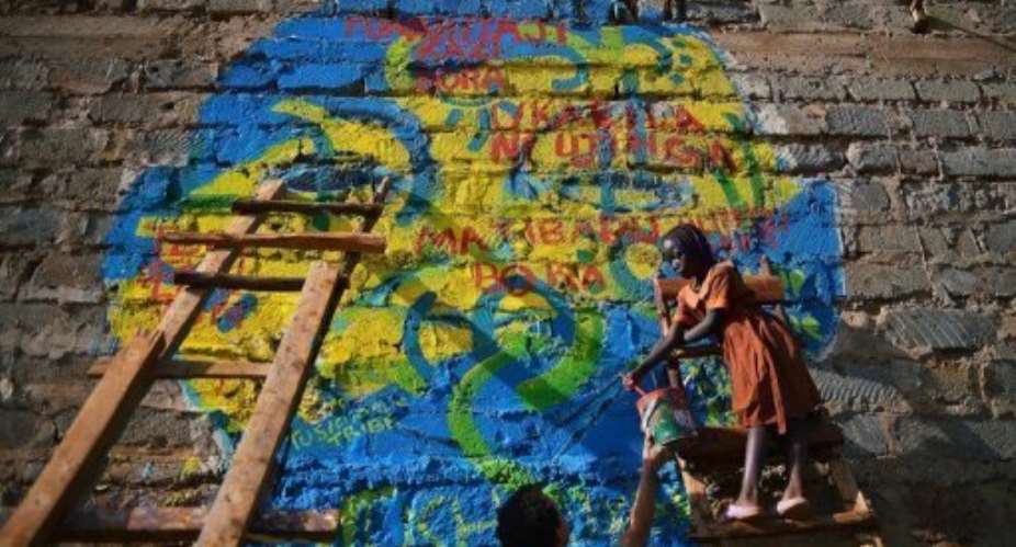 Ten-year-old Harriet (R) helps to paint a mural in Kiberas slum on February 13, 2013.  By Carl de Souza (AFP)
