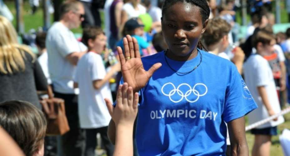 Kenya-born Bosnian marathon runner Lucia Kimani R high-fives a Bosnian boy after a race with other members of the Bosnian Olympic team, during Olympic Day, in Sarajevo, on May 27, 2016.  By Elvis Barukcic AFP