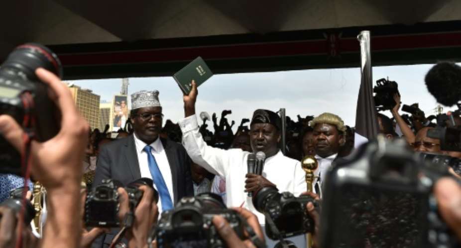 Kenya's opposition leader Raila Odinga holds up a bible as he swears himself in as the 'people's president' before thousands of supporters at a January 30 mock ceremony in Nairobi.  By TONY KARUMBA AFPFile