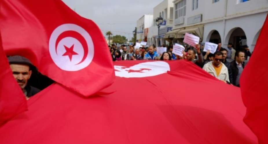 Tunisians wave banners and their national flag during a demonstration in Midoun, north east of Djerba on March 20, 2015, two days after gunmen attacked the National Bardo Museum.  By Robert Michael AFPFile