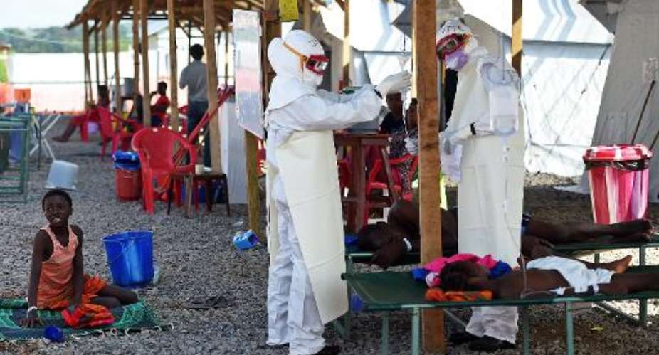 Health workers wearing personal protective equipment assist an Ebola patient at the Kenema treatment centre in Kenema, Sierra Leone on November 15, 2014.  By Francisco Leong AFPFile