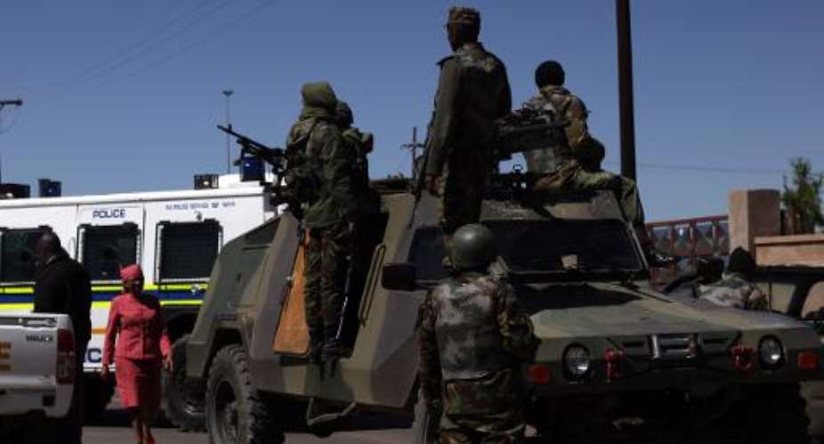 Members of the Lesotho national are seen next to a South African Police armoured vehicle outside Maseru on October 1, 2014.  By Hlompho Letsielo (AFP)