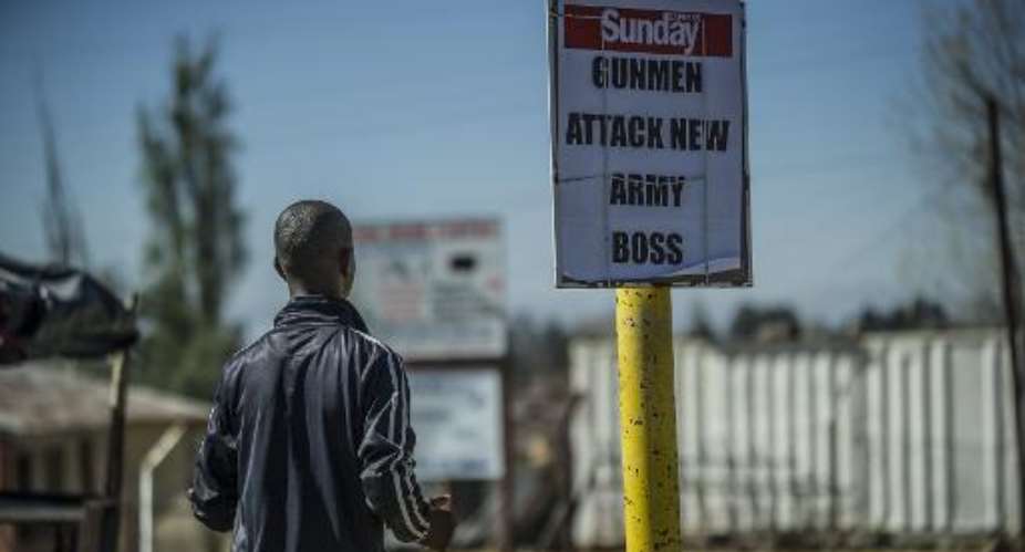 A man stands next to a newspaper headline describing the military coup in Maseru, Lesotho, on August 31, 2014.  By Mujahid Safodien AFPFile