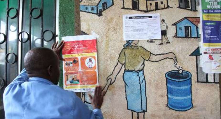 A nurse places an information sign about Ebola on a wall of a public health centre in Monrovia, July 31, 2014.  By  AFPFile