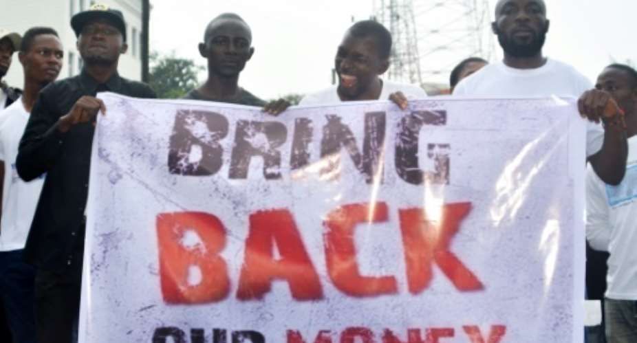 Liberians hold a banner during a demonstration over the disappearance of newly printed bills in September 2018, but the Central Bank of Liberia says the money never went missing.  By Zoom DOSSO AFPFile