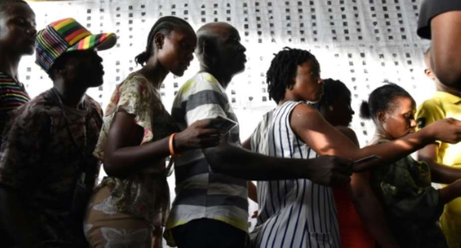Liberians wait outside a polling station to vote in Monrovia.  By ISSOUF SANOGO AFP