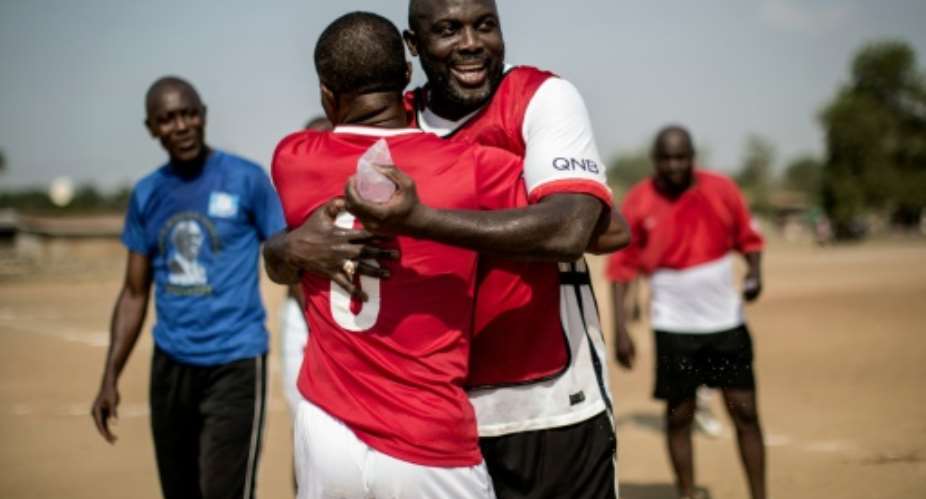 International Liberian soccer star and presidential hopeful George Weah embraces a team member at the end of a match played in Monrovia, Liberia on April 30, 2016.  By Marco Longari AFP