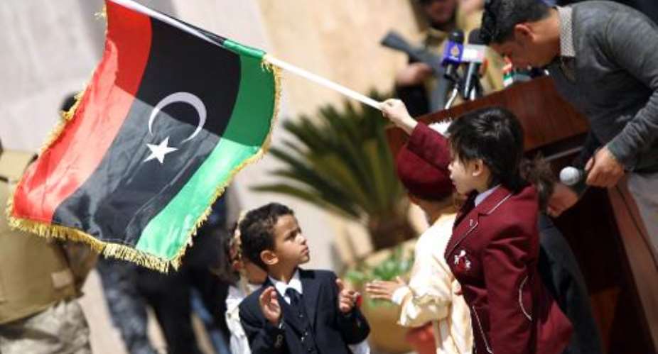 A boy waves the Libyan flag during a ceremony attended by dozens of officials, tribal chiefs and civil society representatives to discuss the countrys new constitution, on April 21, 2014 in the eastern town of Al-Baida.  By Abdullah Doma (AFP)