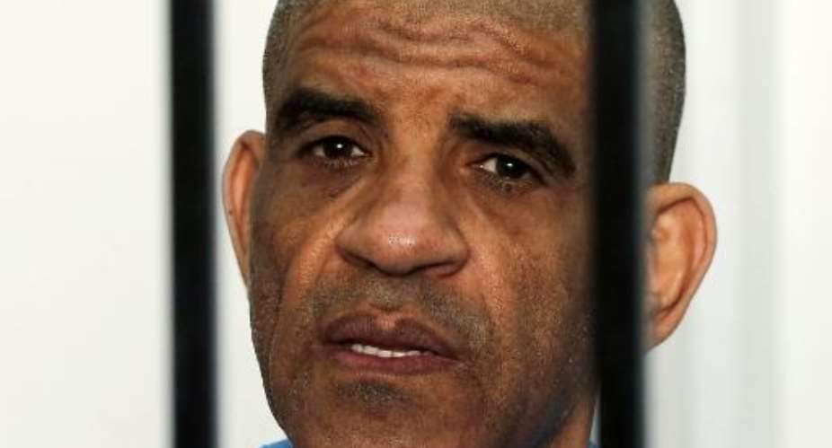 Former Libyan intelligence chief Abdullah al-Senussi, dressed in prison blues, sits behind the accused cell during his trial in a courthouse in Tripoli on May 11, 2014.  By Mahmud Turkia AFP