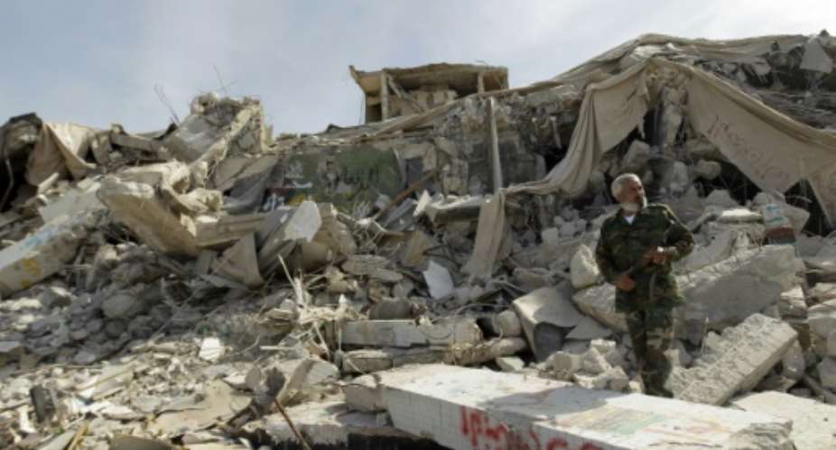 A Libyan fighter walks amidst rubble.  By Joseph Eid AFPFile