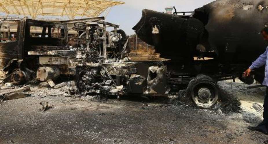 The wreckage of a truck and an airplane are seen at Tripoli international airport in the Libyan capital on July 14, 2014.  By Mahmud Turkia AFP