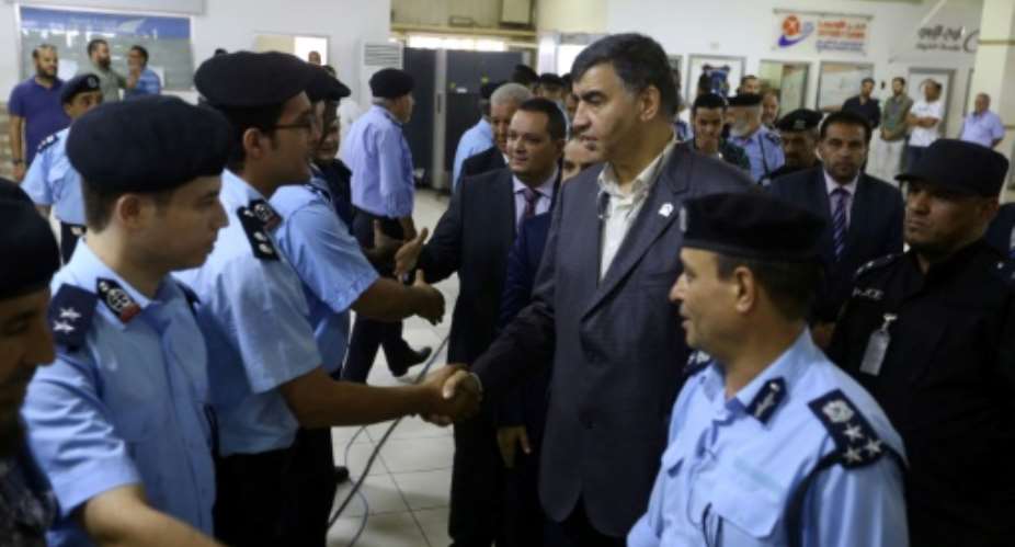 Libyan Interior Minister Abdessalam Ashour C-R and undersecretary of the Ministry of Communications in the Al-Wefaq Government Hisham Abu Shkiwat C-L greet members of the security forces for Tripoli's Mitiga International Airport.  By MAHMUD TURKIA AFP