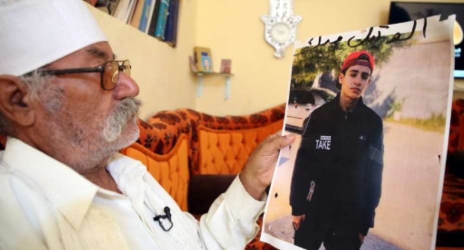Libyan Mohamed al-Magri holds a picture of his 20-year-old missing son Haitham who he believes was killed and buried in a mass grave in the western city of Tarhuna after armed men took him from his home a year ago.  By Mahmud TURKIA AFP