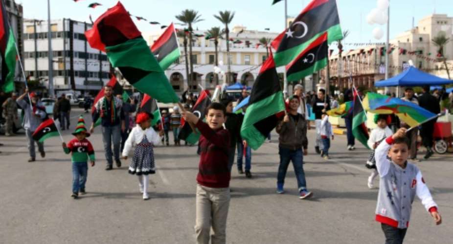 Libyans wave their national flag at Martyr's Square in Tripoli on February 17, 2016 as they celebrate the fifth anniversary of the toppling of Moamer Kadhafi.  By Mahmud Turkia AFP