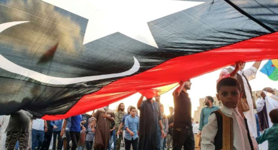 Libyans march in Tripoli with a giant national flag during a September demonstration in support of the UN-recognised government and against strongman Khalifa Haftar who has led an offensive on the capital city since April.  By Mahmud TURKIA AFP
