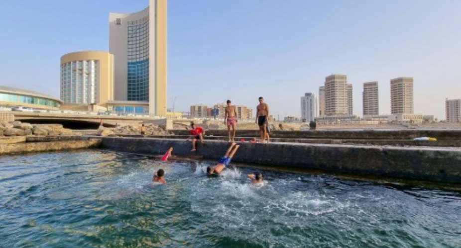 Libyans swim in the Mediterranean at the capital Tripoli's waterfront. Libya's infrastructure has been devastated by a decade of conflict, state collapse and neglect since the 2011 overthrow and killing of dictator Moamer Kadhafi.  By Mahmud TURKIA AFP