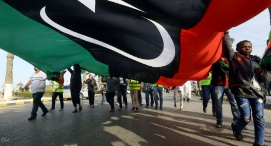 Libyans wave a giant national flag during a demonstration in Tripoli on Friday, in protest against strongman Khalifa Haftar.  By Mahmud TURKIA AFP