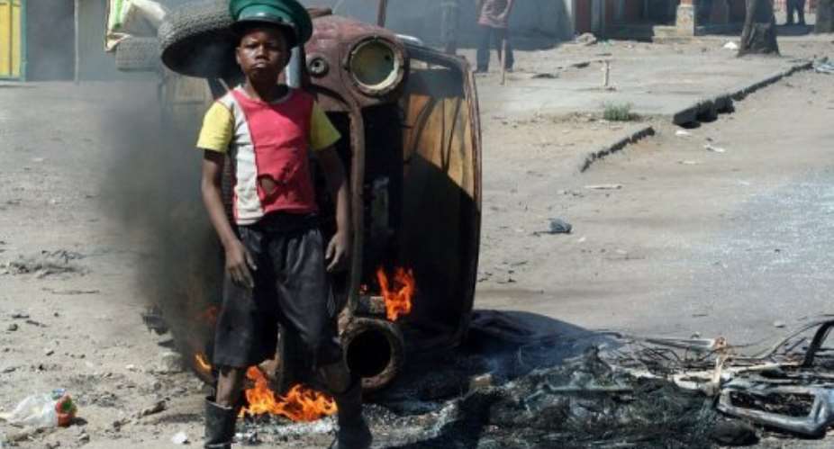A protester stands near a burning car in Maputo amid unrest over poverty on September 2, 2010.  By Sergio Costa AFPFile