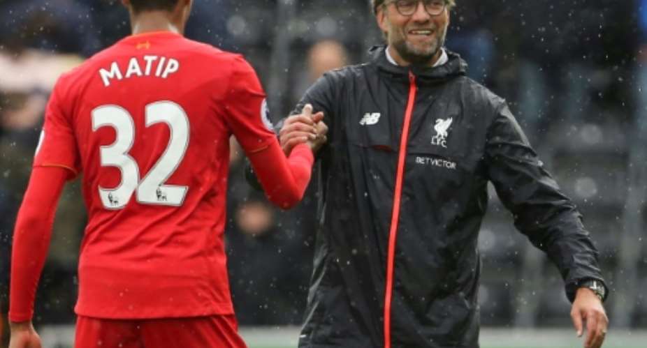 Liverpool manager Jurgen Klopp right shakes hands with defender Joel Matip at the Liberty Stadium in Swansea, south Wales, on October 1, 2016.  By GEOFF CADDICK AFPFile