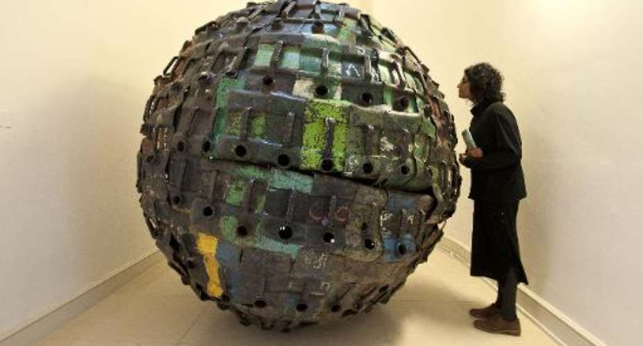 A visitor looks at Giant Ball by Beninese artist Romuald Hazoum at the Contemporary African Arts Fair at Somerset House in Central London on October 15, 2013.  By Will Oliver AFP