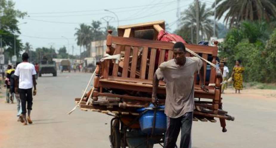 A man pulls a cart full of pieces of furnitures he looted as he walks near a convoy of French soldiers on February 9, 2014 in Bangui.  By Issouf Sanogo AFP