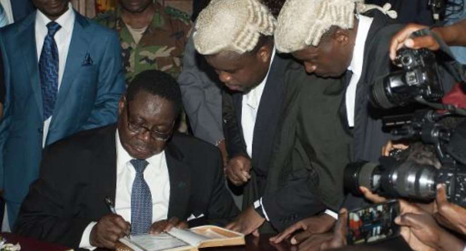 Newly-elected president Peter Mutharika (C-R) signs a document as he takes an oath of office at the High Court in Blantyre, Malawi on May 31, 2014.  By Amos Gumulira (AFP/File)