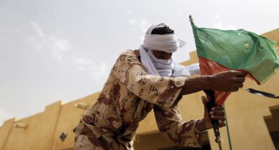 A soldier of the rebel National Movement for the Liberation of Azawad MNLA fixes a MNLA flag at their headquarters on July 27, 2013 in the northern Malian city of Kidal.  By Kenzo Tribouillard AFPFile
