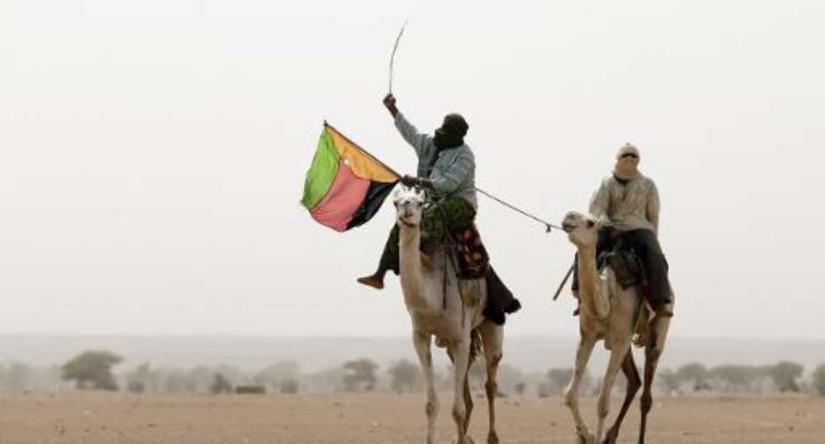 A man holds the flag of the National Movement for the Liberation of Azawad MLNA during a demonstration in support of the MLNA on July 28, 2013 in Kidal, northern Mali.  By Kenzo Tribouillard AFPFile