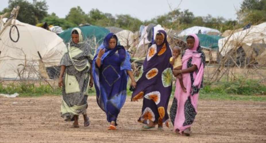Malian refugee women walk next to tents inside the Mentao refugee camp.  By Ahmed Ouoba (AFP/File)