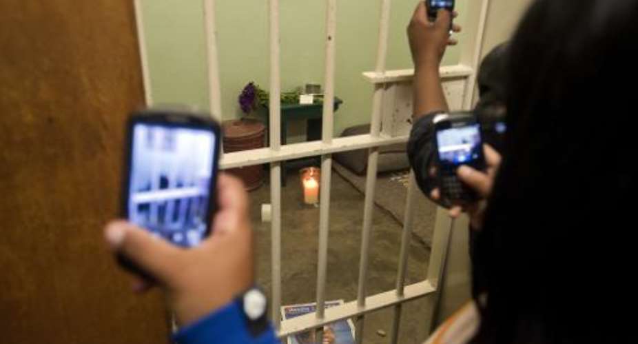 People take pictures of Nelson Mandela's former cell at Robben Island on December 13 2013.  By Rodger Bosch AFPFile